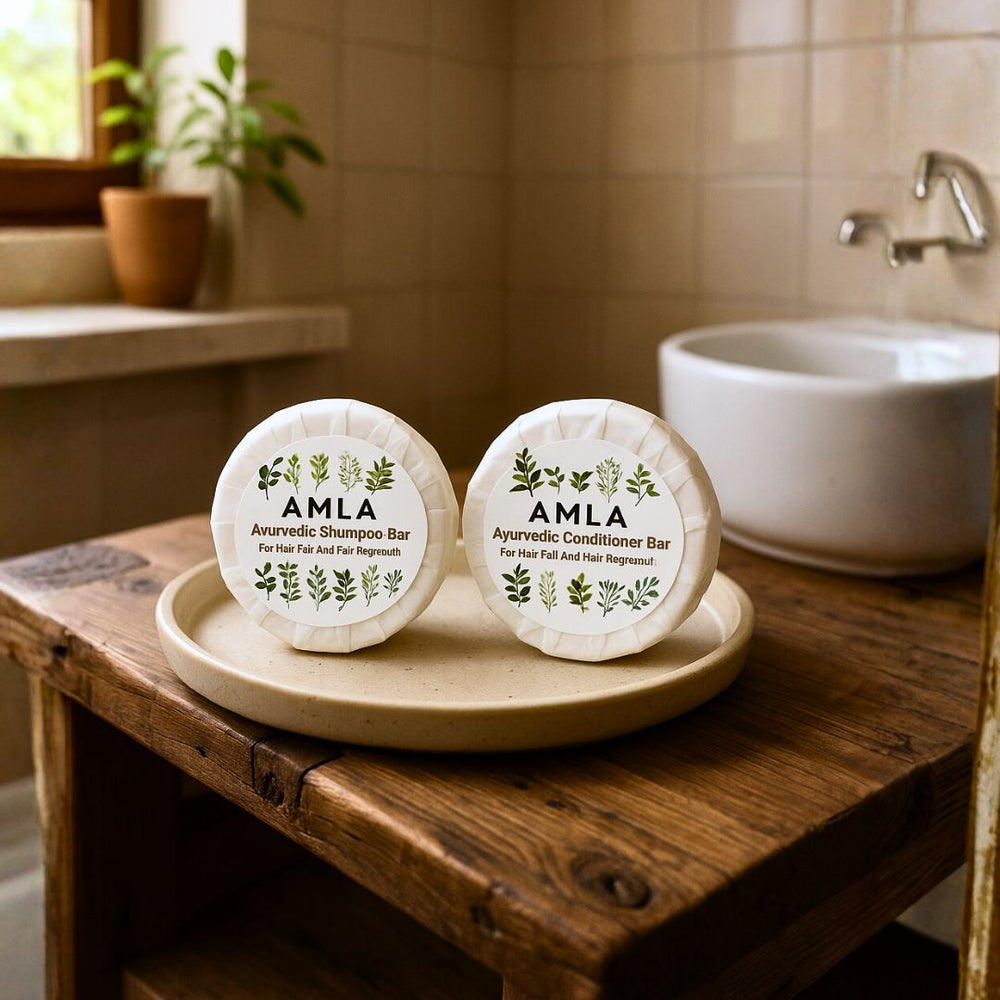 Two AMLA shampoo and conditioner bars on a wooden tray in a bathroom setting.