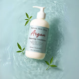 Bottle of Argan Cleansing Conditioner from Nature Skin Shop on a water background with leaves. Bottle of Argan Cleansing Conditioner from Nature Skin Shop on a water background with leaves.