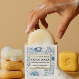 Hand holding a cleansing conditioner bar with 'Nature Skin Shop Clean Locks' packaging on a beige background. Hand holding a cleansing conditioner bar with 'Nature Skin Shop Clean Locks' packaging on a beige background.