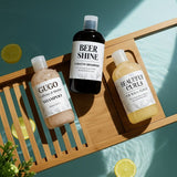 Three bottles of shampoo on a wooden surface with a green background Three bottles of shampoo on a wooden surface with a green background