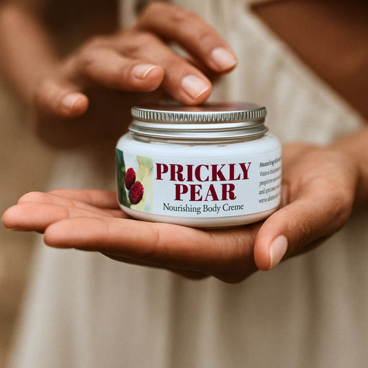 Jar of Prickly Pear Nourishing Body Creme held in a hand with a blurred background