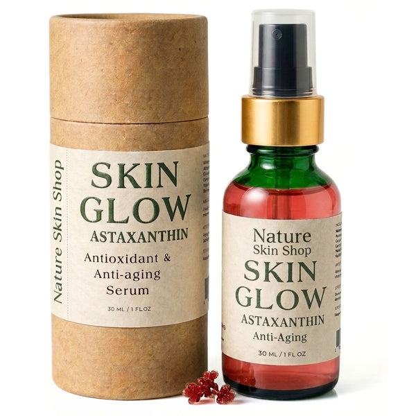A bottle of Nature Skin Shop Skin Glow Astaxanthin anti-aging serum next to its brown kraft paper packaging cylinder, with a few red astaxanthin crystals in front, on a white background.