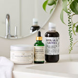 Hair care products including shampoo, conditioner, and serum on a bathroom counter.