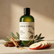 Bottle of 'Apple Cider' shampoo with apples, cinnamon sticks, and leaves on a beige background