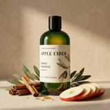 Bottle of 'Apple Cider' shampoo with apples, cinnamon sticks, and leaves on a beige background