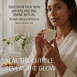 A woman in a cream robe holds a round beige cosmetic compact in a bright bathroom setting. Text on the image reads, 'DISCOVER OUR NEW pH-BALANCING SHINE RITUAL Restore Natural Brilliance Swipe to discover how' and 'SEAL THE CUTICLE, REVEAL THE GLOW.
