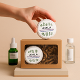 Hand holding an AMLA Ayurvedic Conditioner Bar above a box with more bars, on a beige background.