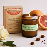 Ancient Incense candle with packaging, grapefruit, rose, and raisins on a light background