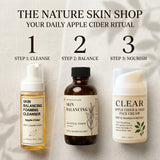 Three skincare products arranged on a light fabric background with large step numbers and text reading 'THE NATURE SKIN SHOP' and 'YOUR DAILY APPLE CIDER RITUAL.' Step 1 shows a yellow cleansing bottle, Step 2 shows an amber toner bottle, and Step 3 shows a white face cream bottle.