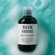 Bottle of Beer Shine Keratin Shampoo on a textured blue background