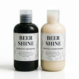 Two bottles of 'Beer Shine' shampoo and conditioner on a white background