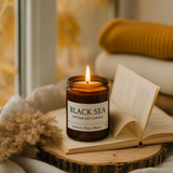 Candle labeled 'Black Sea' on an open book with a blurred indoor background