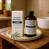 Blemish Recovery Toner bottle and box on a wooden tray with a plant in the background.
