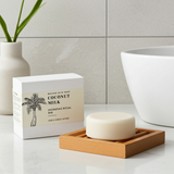 Coconut milk soap bar on a wooden dish with packaging in a bathroom setting