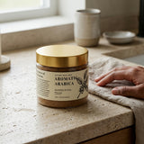 Jar of 'Aromatic Arabica' whipped ritual polish on a kitchen counter with a hand holding a cloth.