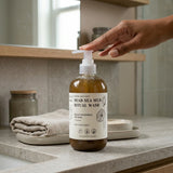 Bottle of Dead Sea Mud Ritual Wash on a bathroom counter with a hand reaching towards it.