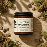Candle jar labeled 'Earth & Oakmoss' on a wooden surface with natural elements.