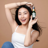 Woman holding a bottle of 'Skin Glow Age' serum against a beige background