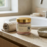 Jar of 'Enchantment' ritual polish on a bathroom counter with a gold lid.