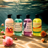 Four bottles of Nature's Skin Shop body wash and foams with floral decorations on a sandy beach.