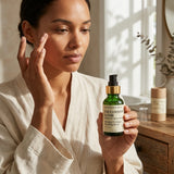 Woman holding a skincare serum bottle in a bright room