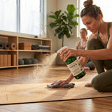 Woman cleaning a wooden floor with a green cleaning spray bottle labeled 'FOCUS'.