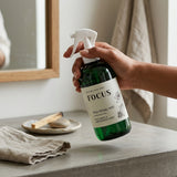 Hand holding a bottle labeled 'FOCUS' on a bathroom counter.