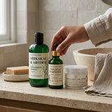 Bathroom counter with Shikakai & Aritha hair care products and a hand holding a bottle.