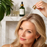 Woman applying a dropper of serum to her hair with a bottle in the background.