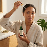 Woman in a bathrobe holding a bottle of Polypeptide Fortifier and a dropper over her face.