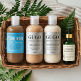 Set of hair care products including shampoo, conditioner, and serum in a basket with fern leaves.