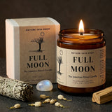 Full Moon candle from Nature Skin Shop with packaging, sage, and crystal on a dark surface