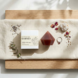 Garnet mineral ritual bar on a wooden surface with eucalyptus leaves and flowers.