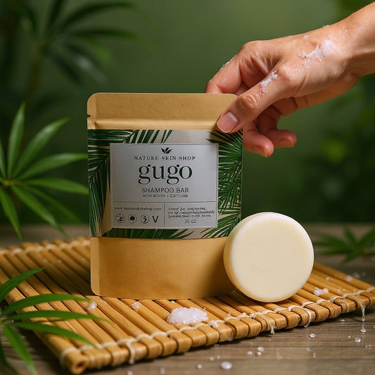 Gugo shampoo bar with packaging on a wooden mat with a green leafy background