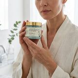 Woman holding a jar of scalp scrub in a bathroom setting