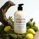 Bottle of 'Amazing Marula' cleansing conditioner with natural elements like a pineapple and fruit on a green background.