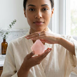 Woman holding a pink crystal in a bright room with natural light