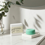 Green soap bar on a white surface with 'Sansa' packaging in the background.