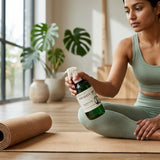 Woman in green athletic wear holding a bottle of 'Vitality' in a yoga studio setting.