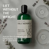 Green bottle of 'Voluminous' conditioner with lavender and leaves on a gray background